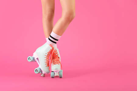 Legs of woman in roller skates on color background