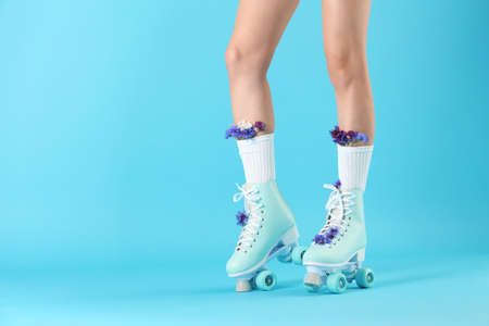 Legs of woman in vintage roller skates and with flowers on color backgroundの写真素材