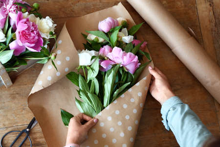 Woman making bouquet of beautiful peonies at tableの写真素材
