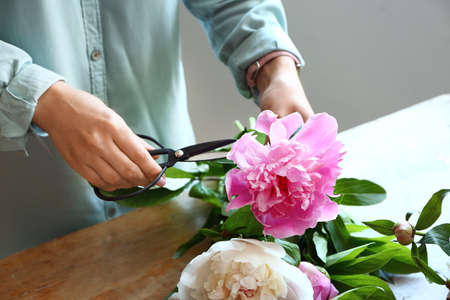Woman making bouquet of beautiful peonies at tableの写真素材