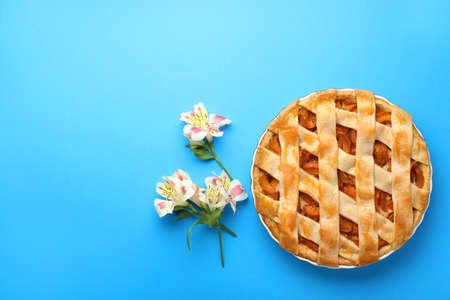 Tasty peach pie and flowers on color backgroundの写真素材