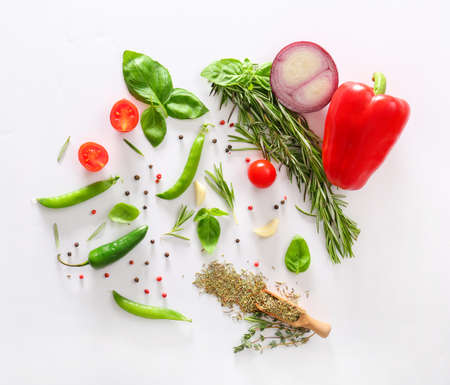 Fresh herbs with vegetables and spices on light background