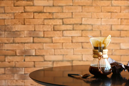 Jar with hot coffee on table against brick backgroundの写真素材