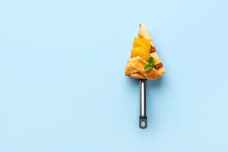 Piece of tasty peach pie on color background