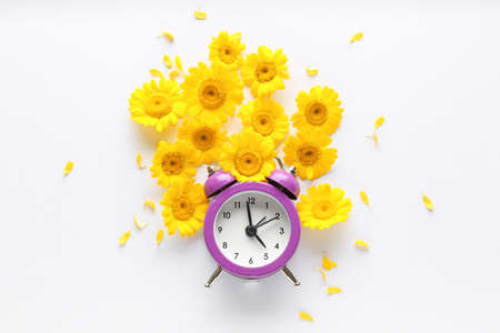 Beautiful composition with flowers and alarm clock on white backgroundの写真素材