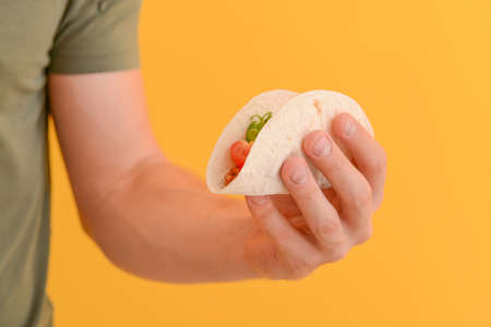 Male hand with tasty taco on color backgroundの写真素材