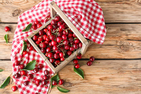 Basket with sweet ripe cherry on wooden tableの写真素材