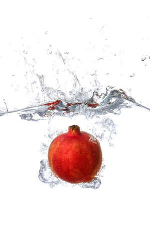 Falling of pomegranate into water on white backgroundの写真素材