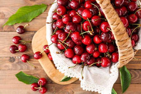 Basket with sweet ripe cherry on wooden tableの写真素材