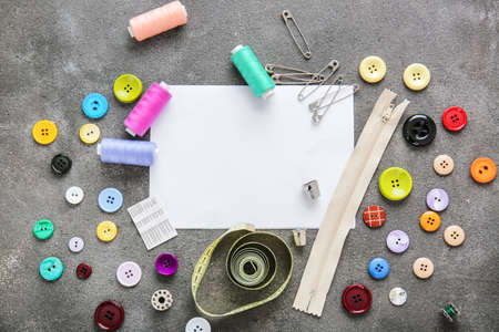 Set of sewing threads with accessories and sheet of paper on gray backgroundの写真素材