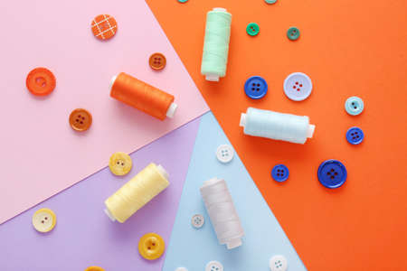 Set of sewing threads and buttons on color background
