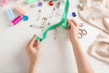 Female hands with measuring tape and accessories on white background