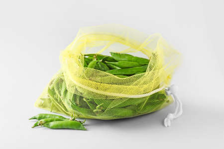 Eco bag with peas on light background