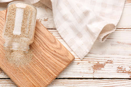 Overturned glass jar with white poppy seeds on wooden tableの写真素材