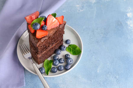 Plate with piece of tasty chocolate cake on color backgroundの写真素材