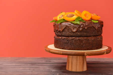 Stand with tasty chocolate cake on table against color backgroundの写真素材