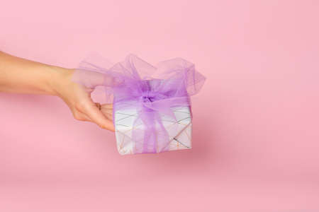 Female hand with gift box on color background