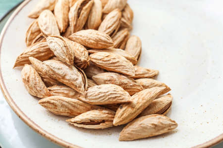 Unpeeled almond nuts on plate, closeup