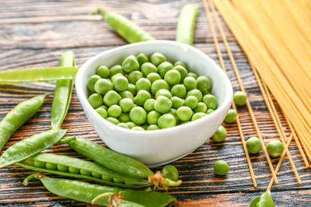 Bowl with tasty fresh peas on wooden tableの写真素材