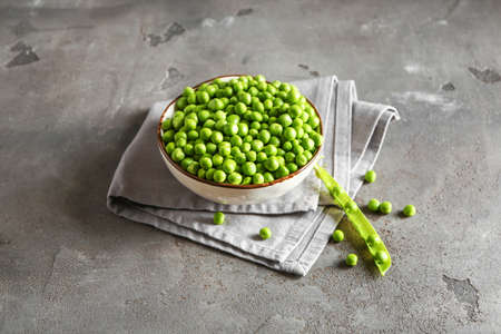 Bowl with tasty fresh peas on grunge background