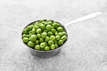 Ladle with tasty fresh peas on gray background
