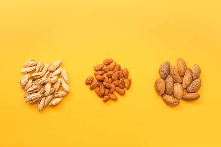 Peeled and unpeeled almonds on color background