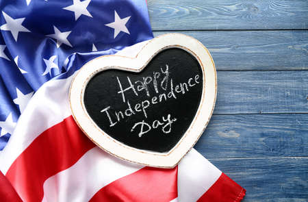Chalkboard with text HAPPY INDEPENDENCE DAY and national flag of USA on wooden tableの写真素材