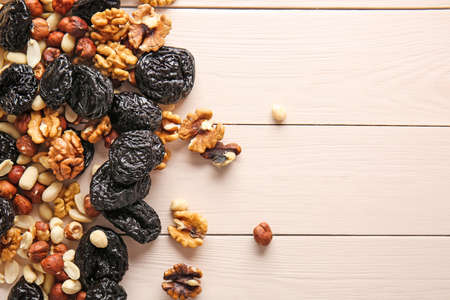 Tasty prunes with nuts on white wooden background