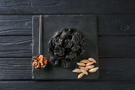 Slate plate with tasty prunes and walnut on dark wooden backgroundの写真素材
