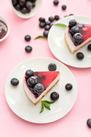 Pieces of tasty blueberry cheesecake on color background