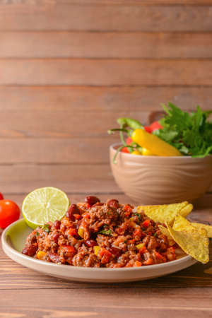 Plate with tasty chili con carne on wooden tableの写真素材