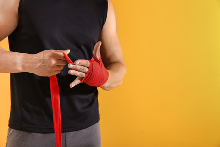 Sporty young man applying wrist bands against color backgroundの写真素材