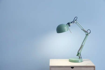 Beautiful stylish lamp on table against color backgroundの写真素材