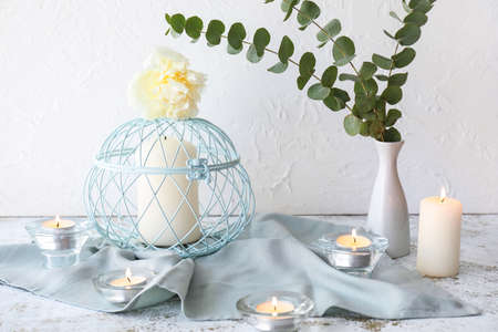 Beautiful burning candles with eucalyptus on light backgroundの写真素材