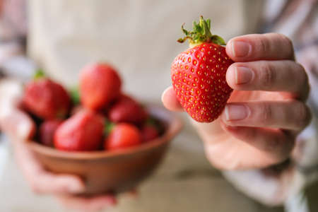 Woman with ripe strawberry, closeup