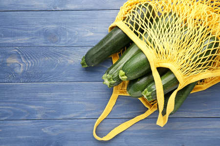 Mesh shopping bag with fresh zucchini squashes on wooden backgroundの写真素材