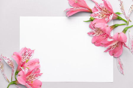 Beautiful fresh flowers and blank card on light backgroundの写真素材