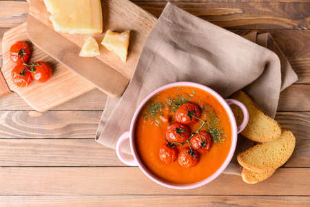 Pot of tasty tomato cream soup on wooden tableの写真素材