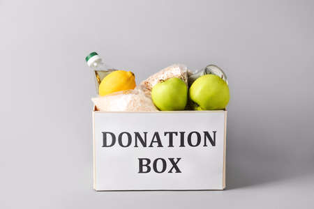 Box with donation food on gray background