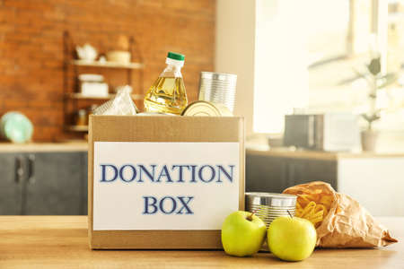 Box with donation food on table in kitchenの写真素材