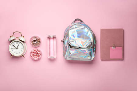 School backpack, clock, bottle of water and stationery on color background