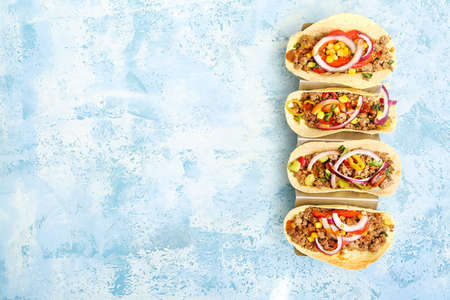 Stand with tasty fresh tacos on color background