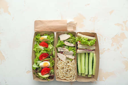 Paper boxes with delicious food on light background