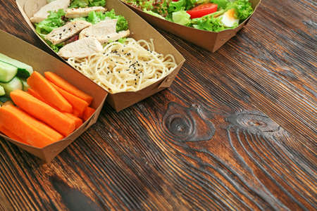 Containers with delicious food on wooden backgroundの写真素材