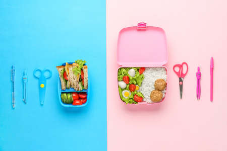 School lunch boxes with tasty food and stationery on color backgroundの写真素材