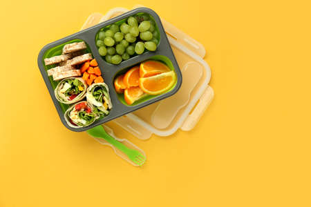 School lunch box with tasty food on color background