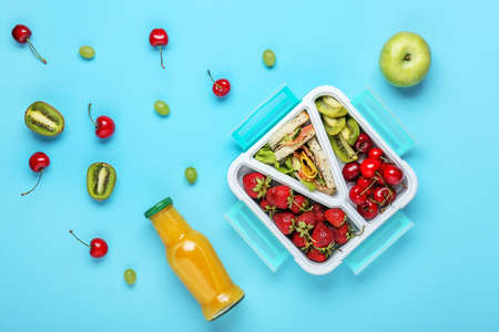 School lunch box with tasty food and bottle of juice on color backgroundの写真素材