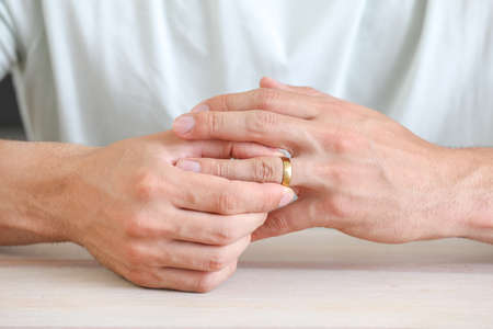 Man taking off his wedding ring at home, closeup. Concept of divorceの写真素材