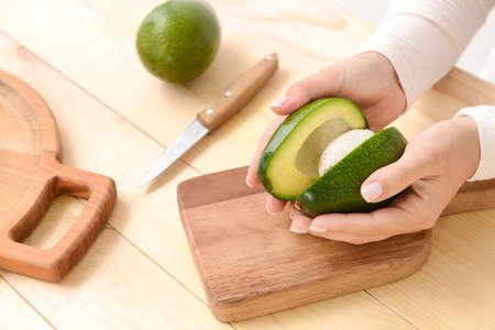 Woman cutting fresh avocado at tableの写真素材