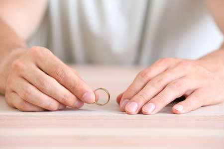 Man with wedding ring at home, closeup. Concept of divorce